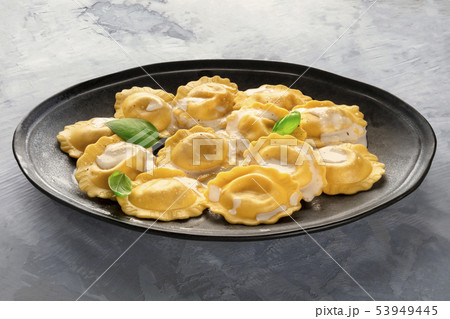 A plate of cooked Italian ravioli garnished with fresh basil leaves A plate of cooked Italian ravioli garnished with fresh basil leaves 53949445