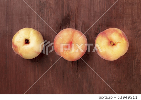 Vibrant organic flat saturn peaches, shot from above on a dark rustic wooden background with a place Vibrant organic flat saturn peaches, shot from above on a dark rustic wooden background with a place 53949511