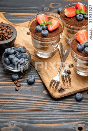 Classic tiramisu dessert with blueberries and strawberries in a glass on wooden background 53952627