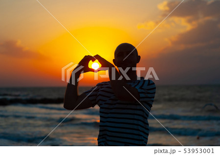 male hands in the form of heart against the sky pass sun beams. Hands in shape of love heart male hands in the form of heart against the sky pass sun beams. Hands in shape of love heart 53953001