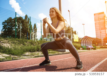 Young sportive girl with curly hairstyle on summer stadium Young sportive girl with curly hairstyle on summer stadium 53959157