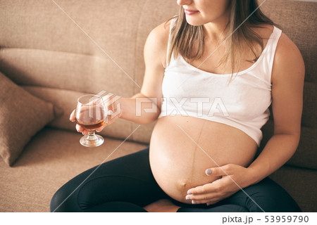 Young future mother keeping glass with alcohol Young future mother keeping glass with alcohol 53959790