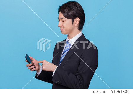 スマホを持つビジネスマン(青背景) スマホを持つビジネスマン(青背景) 53963380