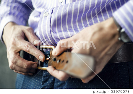 Young Man Puts on a Belt in Trousers Close Up Young Man Puts on a Belt in Trousers Close Up 53970073