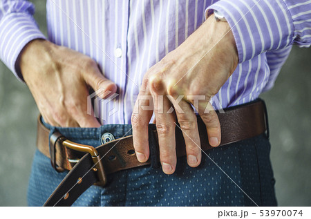 Young Man Puts on a Belt in Trousers Close Up Young Man Puts on a Belt in Trousers Close Up 53970074