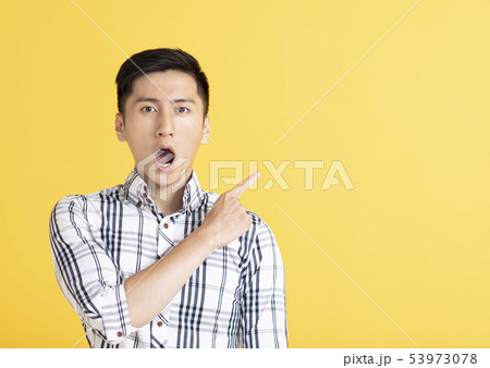 surprised handsome young man pointing surprised handsome young man pointing 53973078