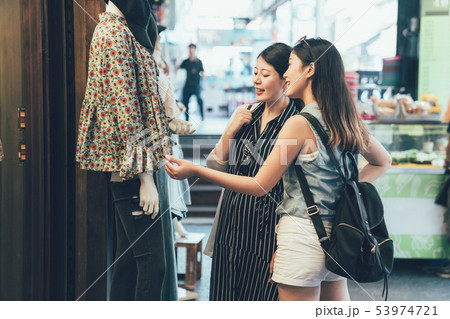 Two female shopaholic friends gazing at lady wear 53974721