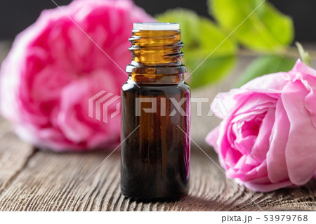 A bottle of rose essential oil with rose flowers A bottle of rose essential oil with rose flowers 53979768