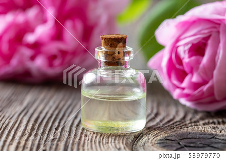A bottle of rose essential oil with rose flowers A bottle of rose essential oil with rose flowers 53979770