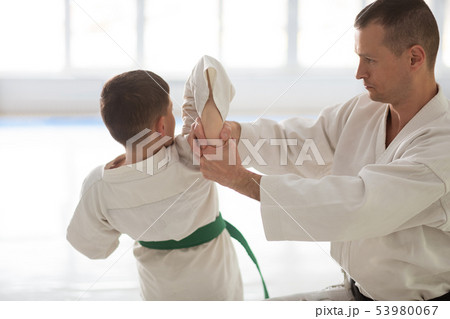 Professional aikido trainer teaching boy during the lesson 53980067