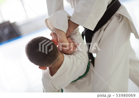 Trainer wearing white kimono and black belt teaching boy 53980069