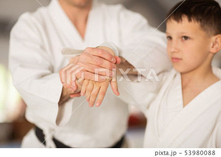 Dark-eyed boy feeling excited learning aikido with trainer 53980088