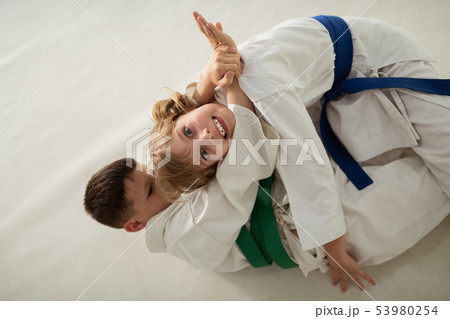 Girl making funny face having aikido battle with friend Girl making funny face having aikido battle with friend 53980254