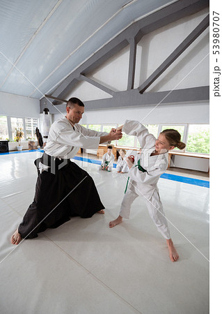 Blonde-haired girl practicing aikido movements with trainer 53980707