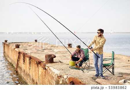 happy friends with fishing rods on pier 53983862
