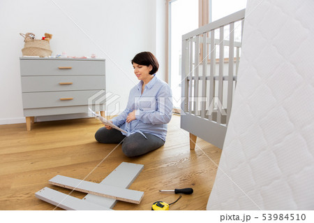 pregnant woman with manual assembling baby bed 53984510