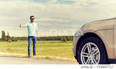 man hitchhiking and stopping car at countryside man hitchhiking and stopping car at countryside 53984717