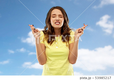 young woman or teenage girl with fingers crossed young woman or teenage girl with fingers crossed 53985217
