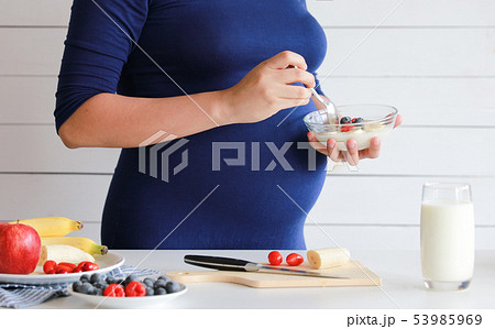 pregnant woman eat a bowl of yogurt and fruits  pregnant woman eat a bowl of yogurt and fruits  53985969