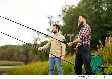 friends with fishing rods at lake or river 53986166