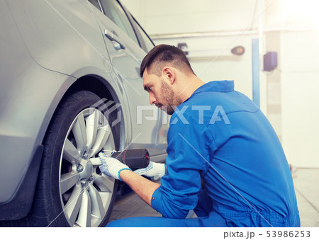 mechanic with screwdriver changing car tire mechanic with screwdriver changing car tire 53986253
