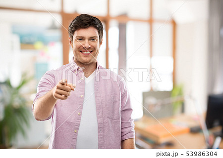 smiling man pointing fingers at you over office smiling man pointing fingers at you over office 53986304