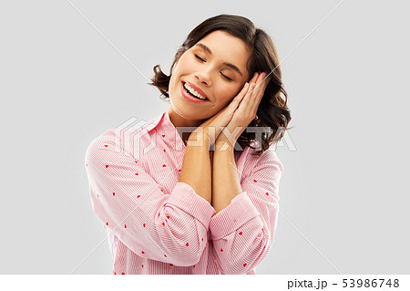 happy woman in pajama making sleeping gesture 53986748