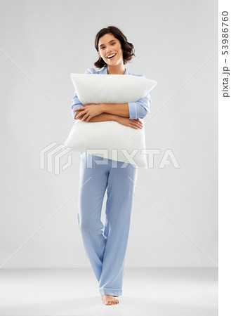 happy young woman in blue pajama hugging pillow happy young woman in blue pajama hugging pillow 53986760