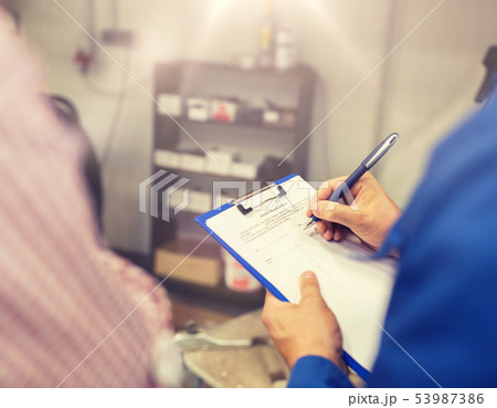 auto mechanic with clipboard and man at car shop auto mechanic with clipboard and man at car shop 53987386