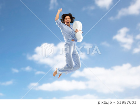 happy woman in pajama jumping with pillow over sky happy woman in pajama jumping with pillow over sky 53987603