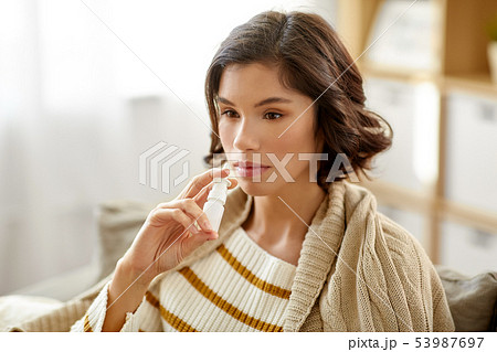 sick woman using nasal spray at home sick woman using nasal spray at home 53987697