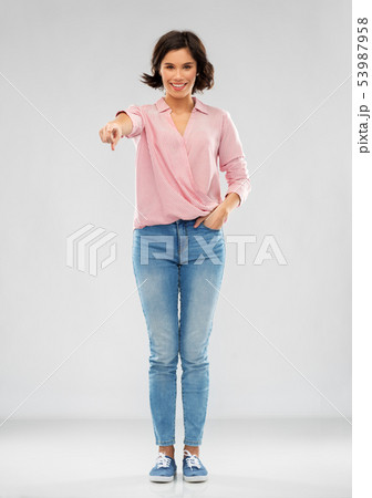 young woman in shirt and jeans pointing to you 53987958