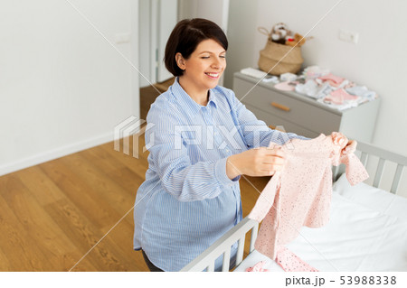 happy pregnant woman setting baby clothes at home happy pregnant woman setting baby clothes at home 53988338