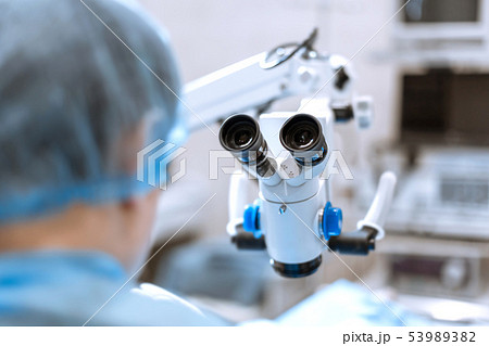 back of surgeon in front of surgical microscope 53989382