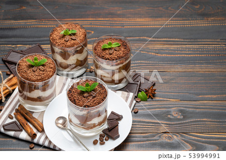 Classic tiramisu dessert in a glass on wooden background Classic tiramisu dessert in a glass on wooden background 53994991