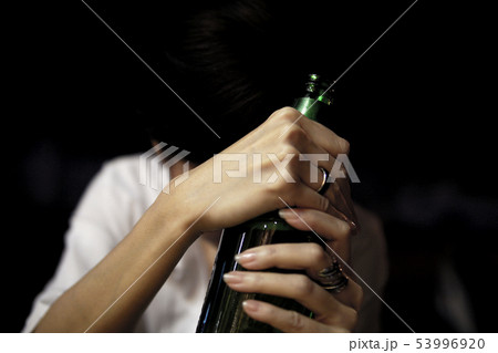 Sad girl holding a bottle of beer in dark Sad girl holding a bottle of beer in dark 53996920