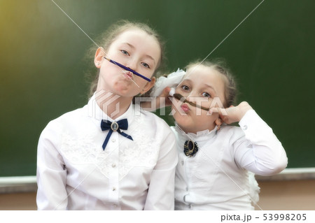 Two sisters at school are laughing at school. Two sisters at school are laughing at school. 53998205