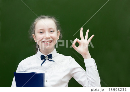 Successful teen schoolgirl smiling holding up her Successful teen schoolgirl smiling holding up her 53998231