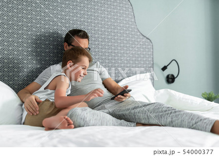 Father and son lying in bed at home 54000377