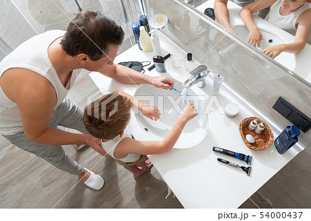 Dad and little son standing in the bathroom near mirror 54000437