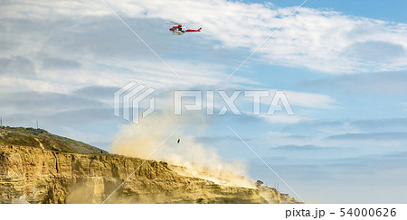 Helicopter in flight on cloudy sky above a cliff Helicopter in flight on cloudy sky above a cliff 54000626