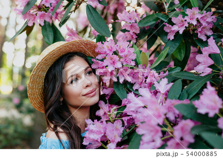 Close up romantic portrait of beautiful elegant woman in straw hat in blossom spring trees. 54000885