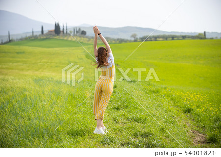 A young woman in bright clothes standing on a green meadow 54001821