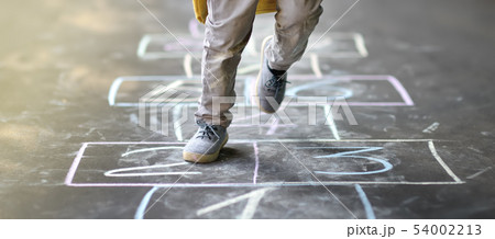 Closeup of little boy's legs and hopscotch drawn 54002213