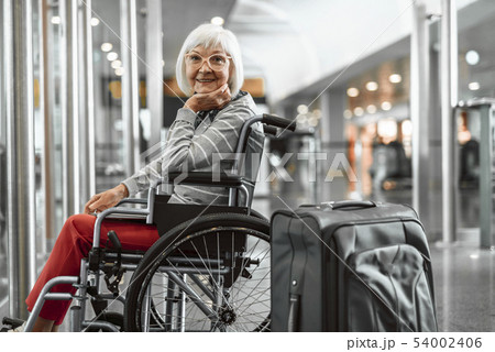 Happy mature lady on disabled carriage waiting for trip at hall Happy mature lady on disabled carriage waiting for trip at hall 54002406
