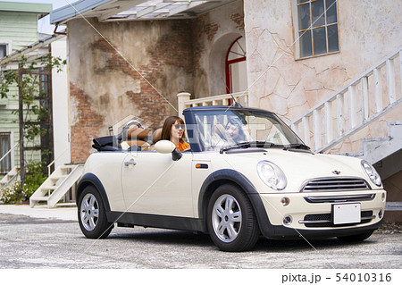 おしゃれな街並みに似合う可愛いオープンカーで観光スポットに繰り出し女子旅を楽しむ可愛い女性二人組の写真素材