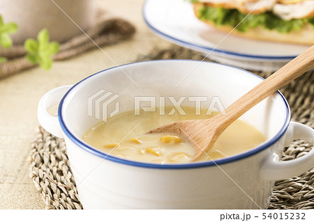 ほんのり湯気の立つ スプーンですくったコーンクリームスープの写真素材