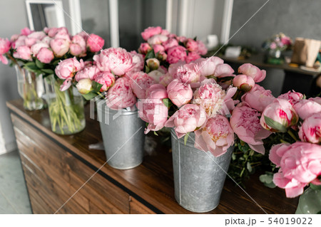 The counter of the flower shop. Pink peonies in a metal vase. Beautiful peony flower for catalog or 54019022