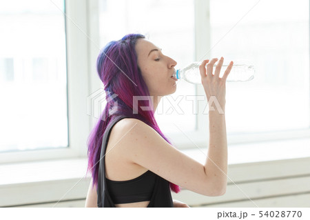 Young girl hipster with colored hair drinks water from a bottle after intense physical training in Young girl hipster with colored hair drinks water from a bottle after intense physical training in 54028770