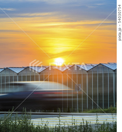 Highway Near the Greenhouse Plant at Sunset. Highway Near the Greenhouse Plant at Sunset. 54030754